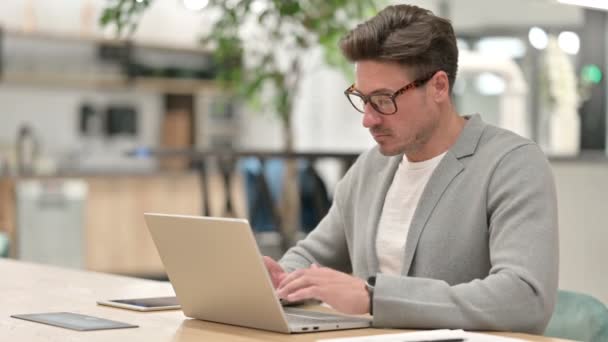 Hombre serio de mediana edad con el ordenador portátil que muestra pulgares hacia abajo — Vídeos de Stock