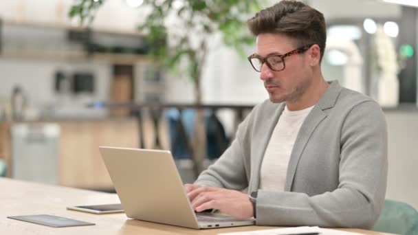 Hombre serio de mediana edad con ordenador portátil mirando a la cámara — Vídeos de Stock