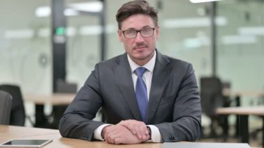 Orta yaşlı işadamı kamerada el sıkışma işareti gösteriyor 