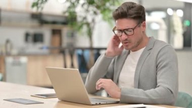 Dizüstü bilgisayarlı orta yaşlı adamın boynu ağrıyor. 