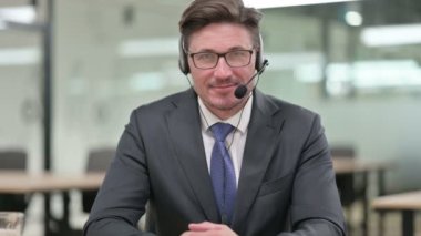 Orta yaşlı iş adamı portresi. Kamera karşısında gülümseyen kulaklıklı. 