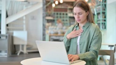 Kafede dizüstü bilgisayarlı hasta genç kadın öksürüyor. 