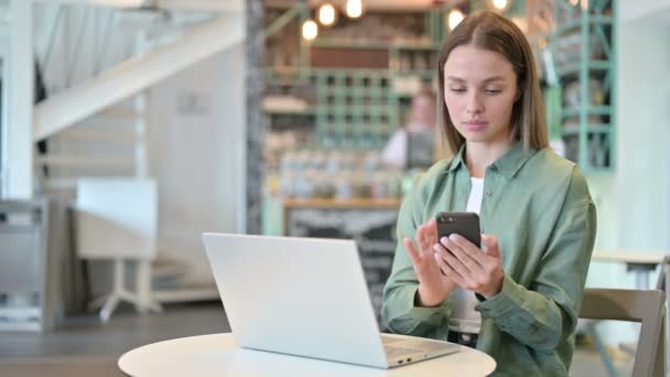 Профессиональная женщина с помощью смартфона и ноутбука в кафе — стоковое видео