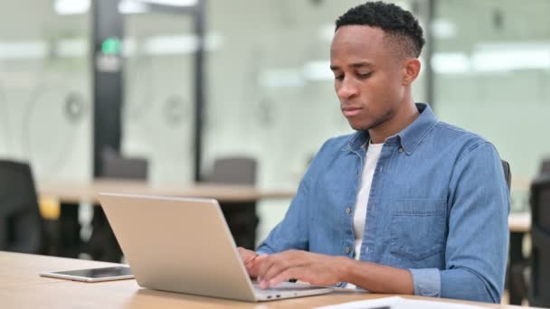 Случайный африканский человек с ноутбуком с болями в запястье в офисе — стоковое видео