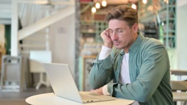 Laptop 'u olan uykulu orta yaşlı adam kafede kestiriyor. 