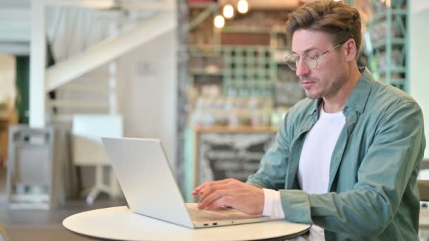 Hombre de mediana edad que trabaja en el ordenador portátil en Café — Vídeos de Stock