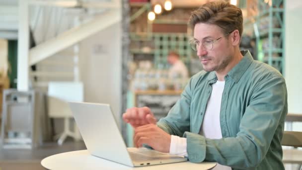 Hombre serio de mediana edad con ordenador portátil mirando a la cámara — Vídeos de Stock