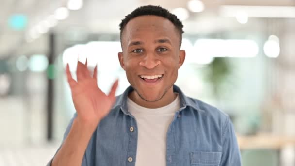 Retrato de un hombre africano casual saludando en una videollamada — Vídeos de Stock