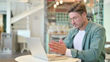 Kafe 'de laptopta düşünen ve çalışan dalgın orta yaşlı adam. 