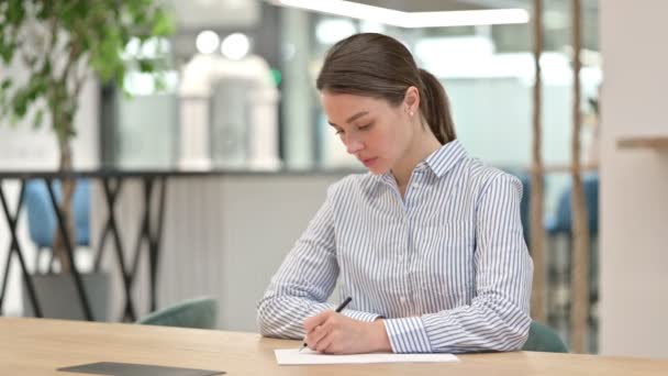 Серьёзная молодая женщина занимается бумажной работой в офисе — стоковое видео