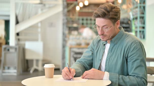 Súlyos középkorú férfi írásban papíron Cafe — Stock videók
