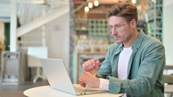 Cansado hombre de mediana edad con el ordenador portátil que tiene dolor de cuello en Café — Vídeos de Stock