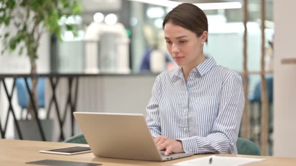 Привлекательная молодая женщина работает на ноутбуке в офисе — стоковое видео