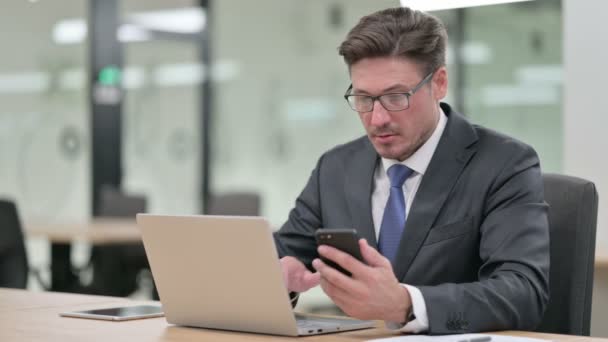 Středověký podnikatel pracující na notebooku a smartphonu v kanceláři — Stock video