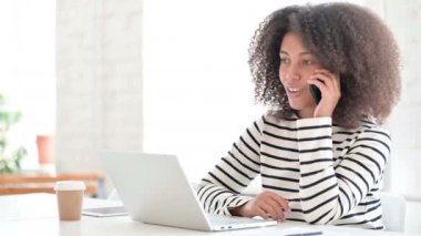 Dizüstü bilgisayarlı Afrikalı Kadın Akıllı Telefonla Konuşuyor 