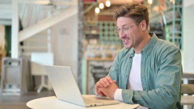 Orta yaşlı adam Cafe 'de laptopta görüntülü sohbet yapıyor. 