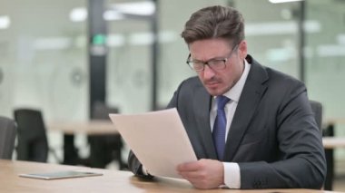 Ofiste evrak işi yapan ciddi bir orta yaşlı işadamı. 