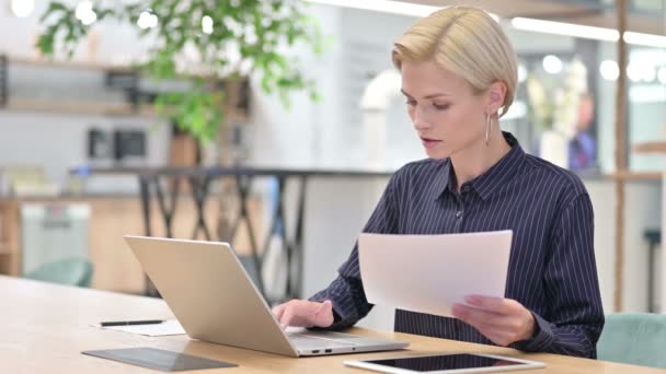 Красивая молодая предпринимательница работает на ноутбуке с документами в офисе — стоковое видео