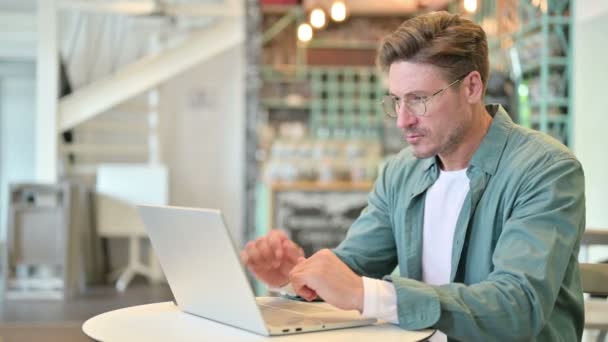 Hombre de mediana edad estresado con el ordenador portátil con dolor de cabeza en Café — Vídeos de Stock