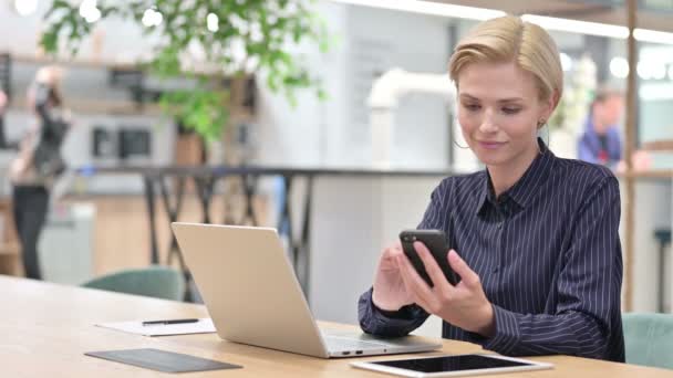 Professionele zakenvrouw met laptop met behulp van Smartphone in Office — Stockvideo