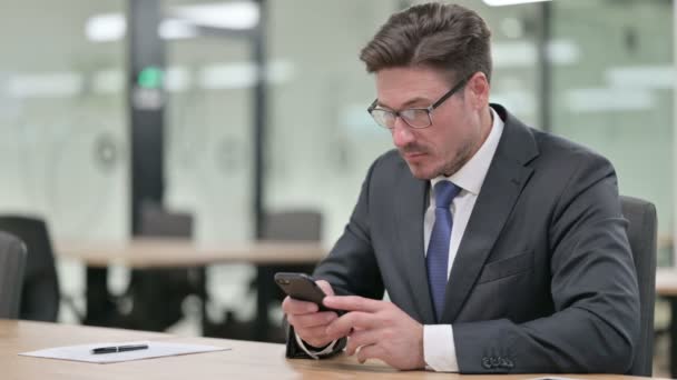 Atractivo hombre de negocios de mediana edad usando Smartphone en Office — Vídeos de Stock