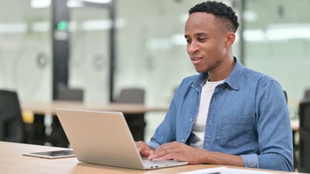 Alkalmi afrikai férfi csinál video Chat a laptopon az irodában — Stock videók