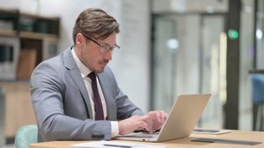 Dizüstü bilgisayarlı Ciddi İşadamı Kameraya Bakıyor