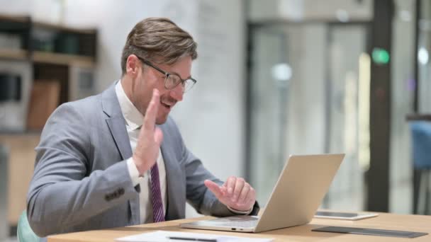 Веселый бизнесмен делает видеозвонок на ноутбуке в офисе — стоковое видео