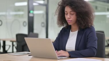 Dizüstü bilgisayarlı neşeli Afrikalı iş kadını Kameraya gülümsüyor 