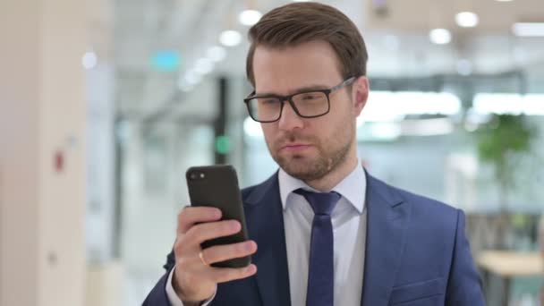 Uomo d'affari Navigazione internet su Smartphone al lavoro — Video Stock