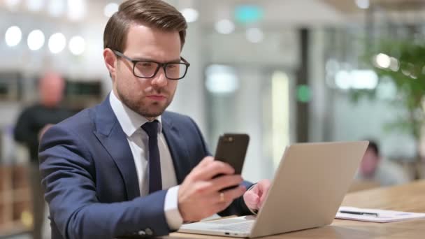 Geschäftsmann bei der Arbeit mit Smartphone und Laptop — Stockvideo