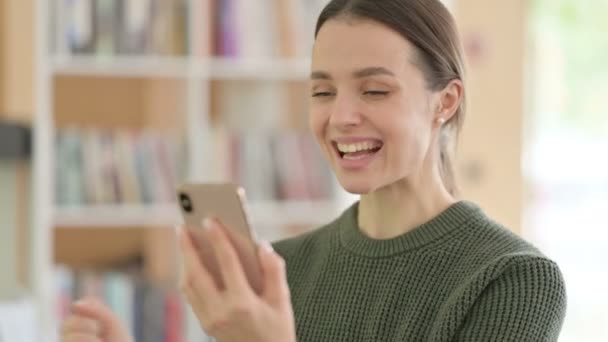 Młoda kobieta świętuje sukces online na smartfonie — Wideo stockowe