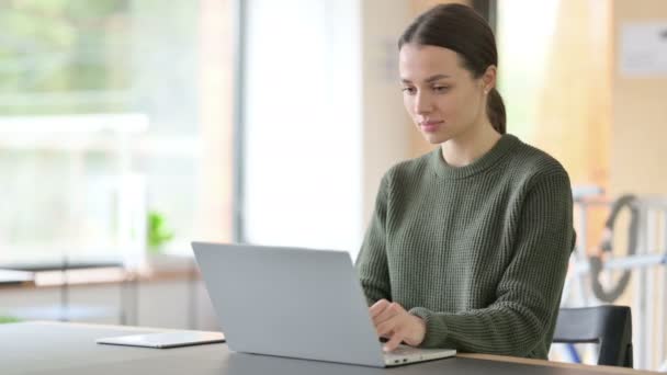 Молода жінка працює на ноутбуці в офісі — стокове відео