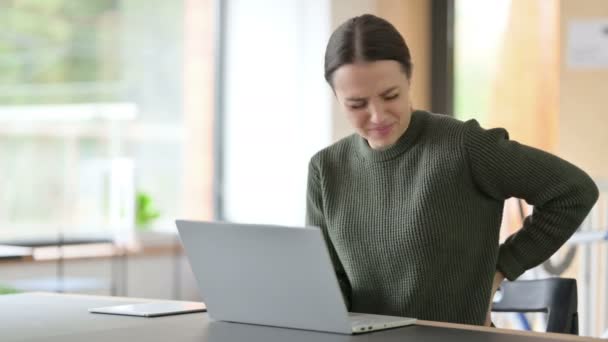 Ung kvinne med laptop som har ryggsmerter – stockvideo