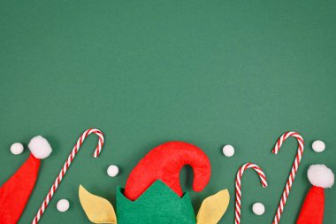 Noel Elf şapkası ve kulakları, şeker kamışları, kırmızı Noel Baba şapkaları ve altta beyaz kartopları ve üstte yeşil arka planda boş fotokopi alanı