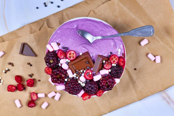 Sağlıklı kırmızı meyve suyu kasesi ahududu, kızılcık, küçük marşmelov ve çikolata parçalarıyla süslenmiş.