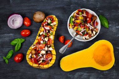 Vejetaryen fırınlanmış kabak dolgulu dolgulu dolma biber, kiraz domatesleri, kırmızı soğan ve mantarlarla kaplı koyu arkaplan