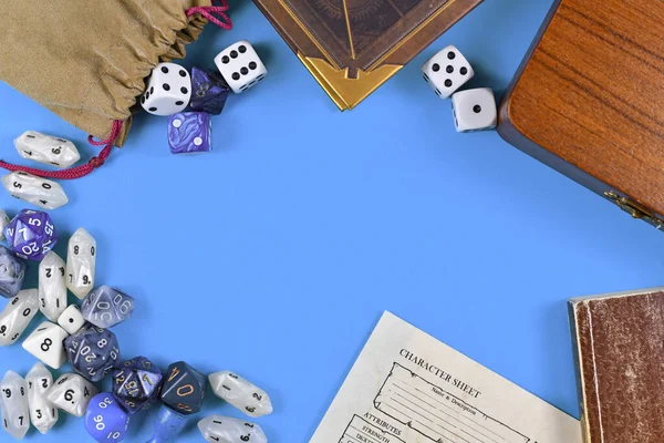 Flat lay concept design for tabletop role playing with blue and white RPG dices, character sheet and rule books with empty copy space on blue background
