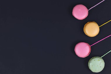 Siyah arkaplanda boş kopya alanı olan dizgilere eklenmiş renkli Fransız badem kurabiyesi