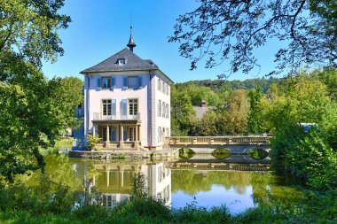 Small cultural heritage baroque castle building called 'Trappenseeschloss' in middle of lake in Heilbronn in Germany on sunny day clipart