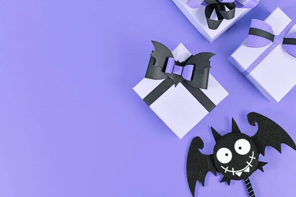 黑色蝴蝶结的万圣节纸制礼品盒 紫色背景旁边有愚蠢的手感蝙蝠 有空白的复制空间 — 图库照片