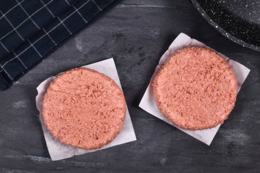 Koyu arkaplanda iki çiğ vegan soya esaslı hamburger köftesi.