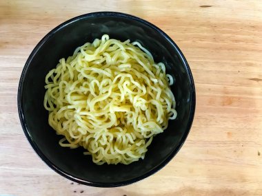 ahşap arka plan üzerinde siyah bir kapta erişte