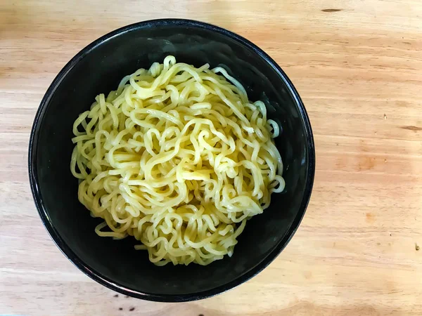 Macarrão em uma tigela preta em fundo de madeira — Fotografia de Stock