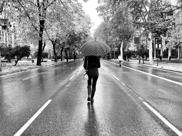 woman walking in the rain with an umbrella on an empty street