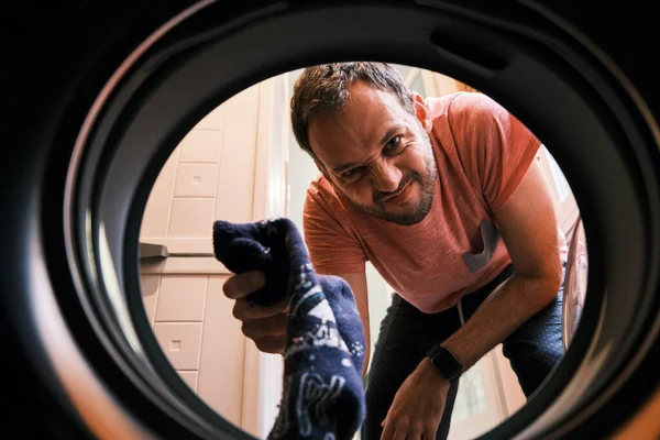 A Man Puts A Pair Of Dirty Socks Inside The Laundry Machine For Washing - Closeup Shot