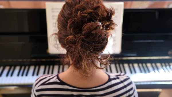 年轻女子弹钢琴从后面看 — 图库照片