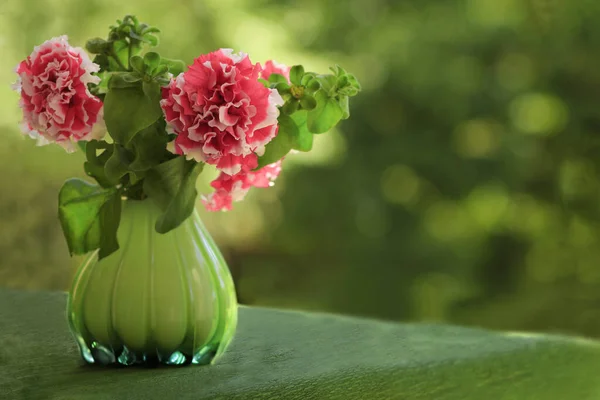 Bukett Med Blommande Rosa Petunior Glasgrön Vas Bordet Grön Bakgrund — Stockfoto