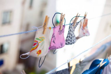 Çamaşır ipinde yıkandıktan sonra evde kuruyan renkli sağlık maskelerinin stok fotoğrafı..