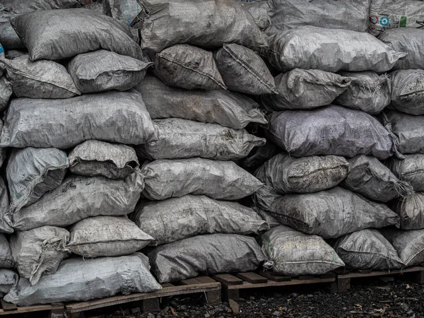 a pile of bags of soil and charcoal lies on the ground A bag for organic fertilizers on the market. (selective focus)